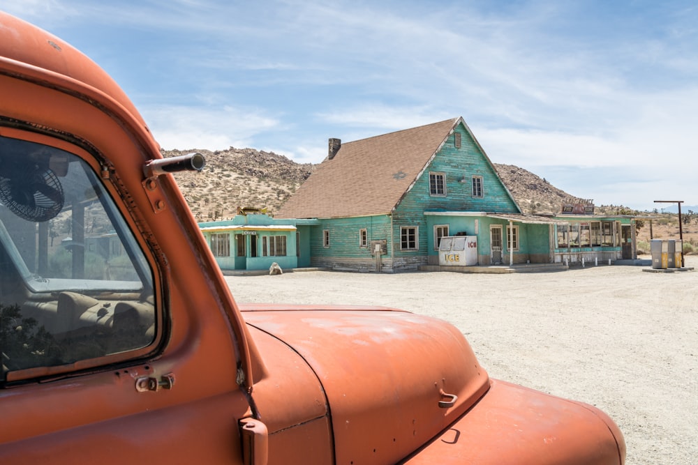 an orange truck parked in front of a green house