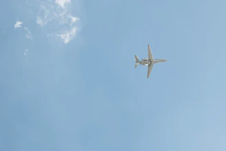 Midsize jet cruising over the Alps with a clear blue sky backdrop.