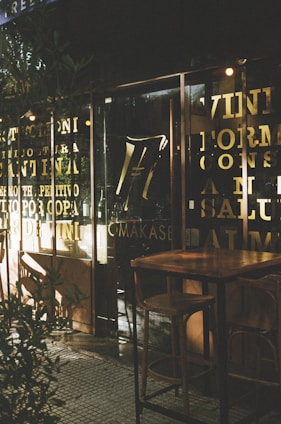A cozy urban café storefront with visible signage and outdoor seating on a sunny day.