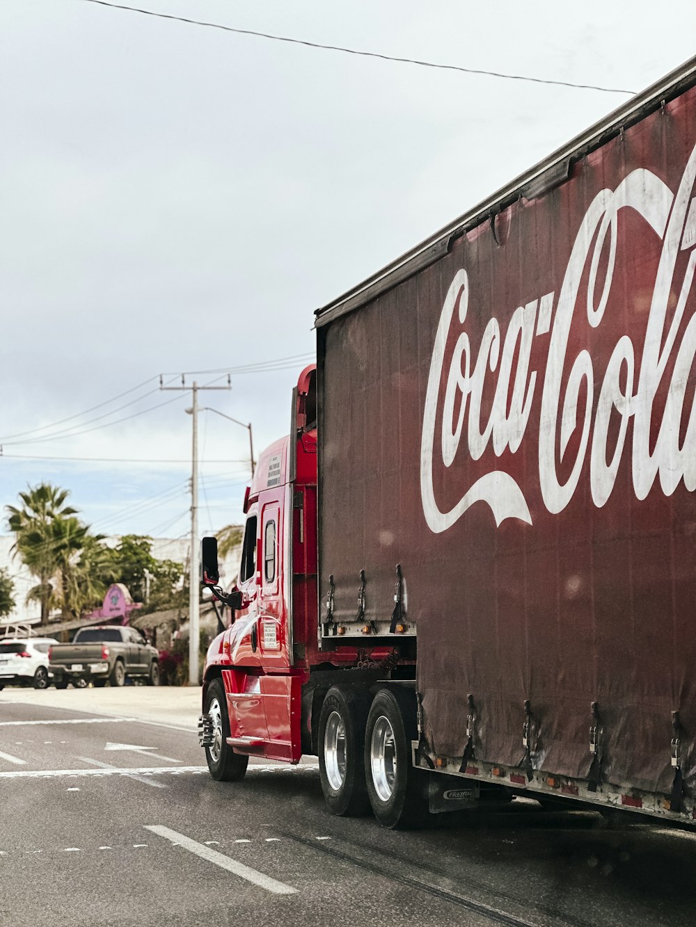 a red coca - cola truck driving down a street