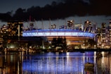 a large stadium lit up at night with a boat in the water