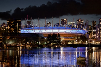 a large stadium lit up at night with a boat in the water