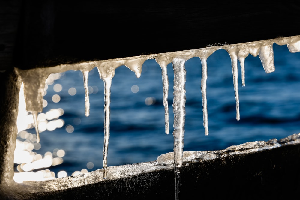 icicles hanging from the side of a building next to a body of water