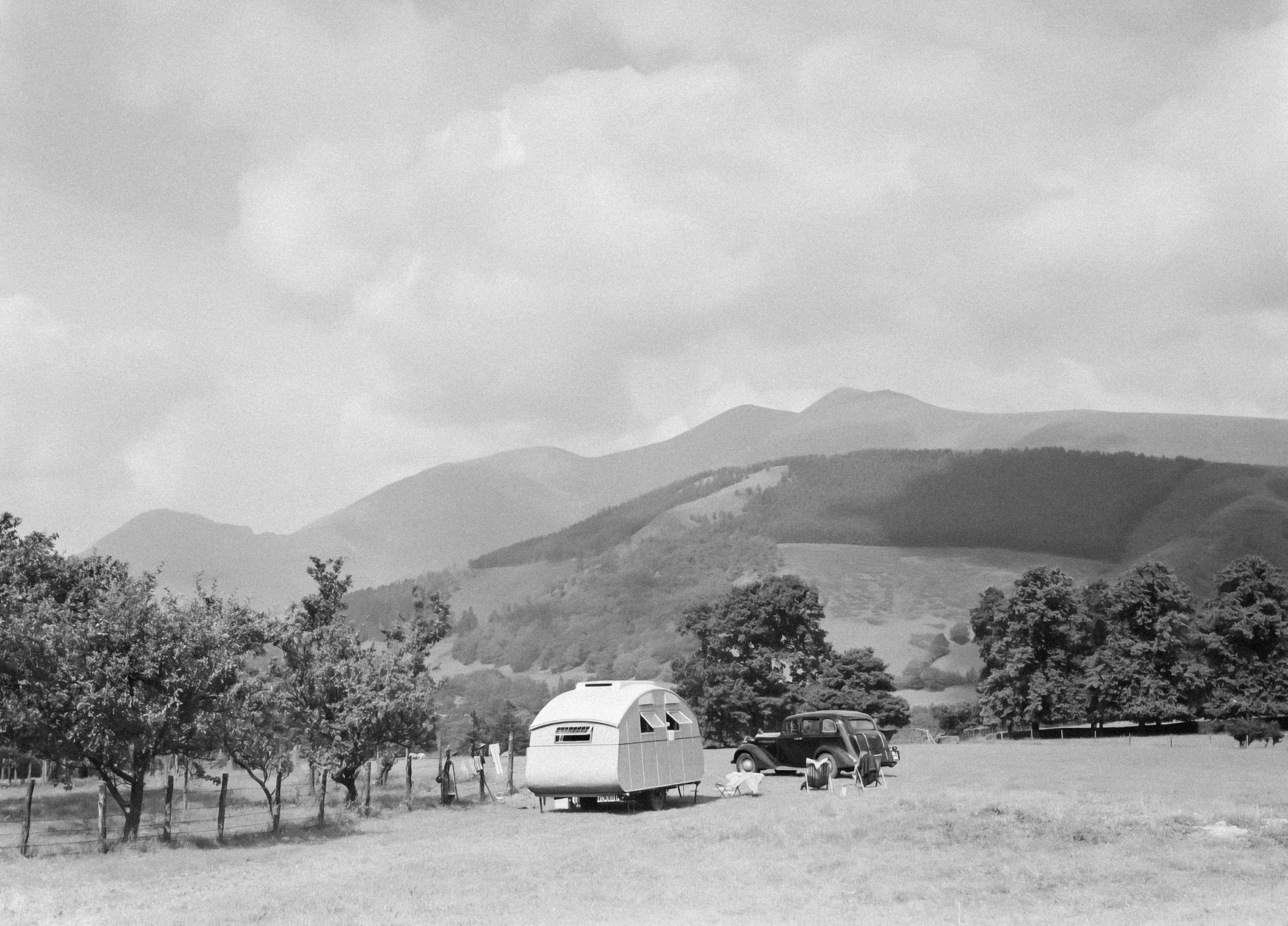 a black and white photo of an rv parked in a field