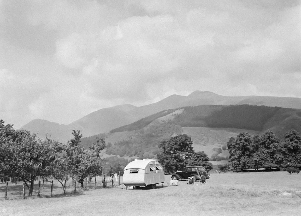 a black and white photo of an rv parked in a field