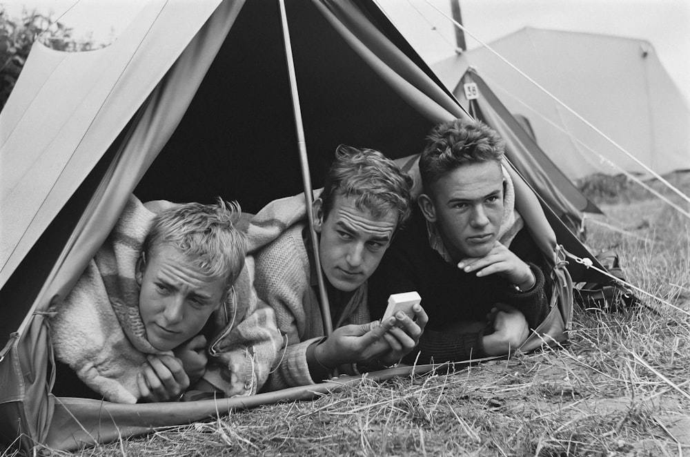 a couple of men laying next to each other in a tent