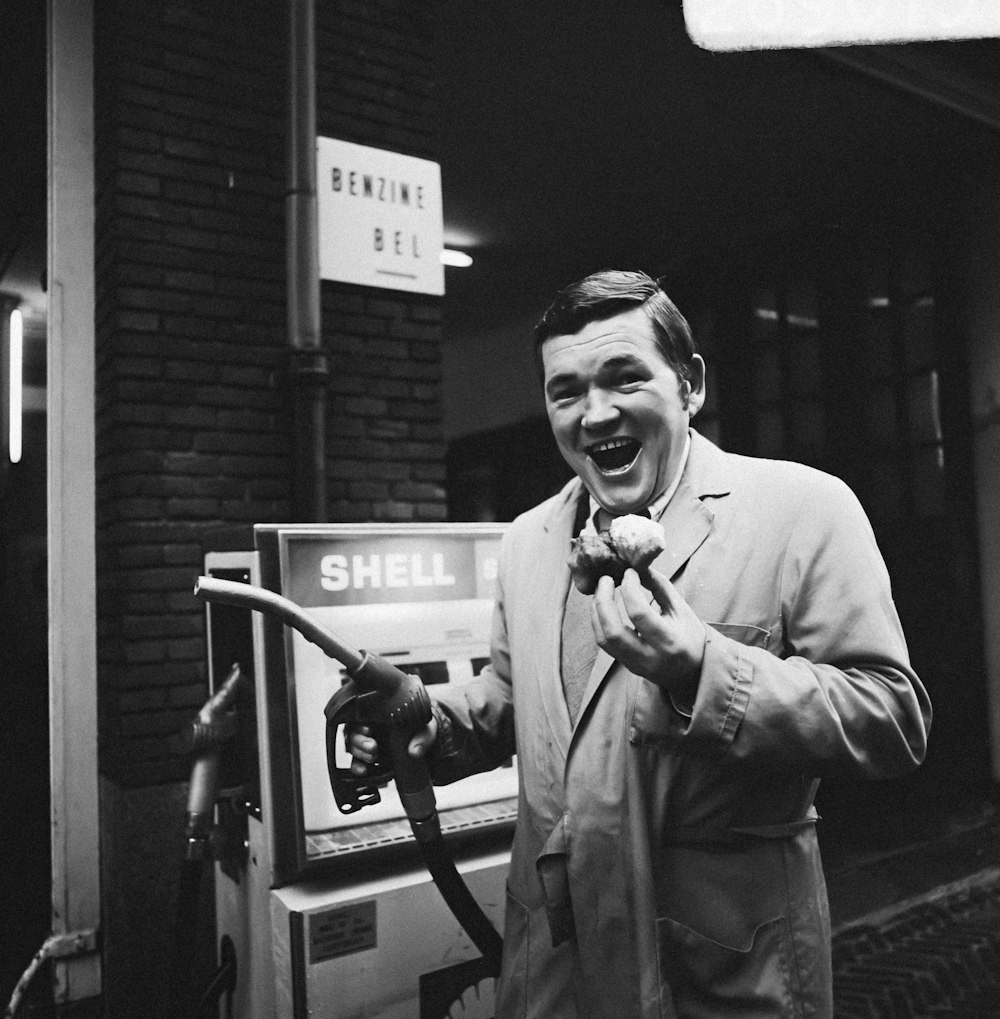 a man in a suit and tie holding a gas pump