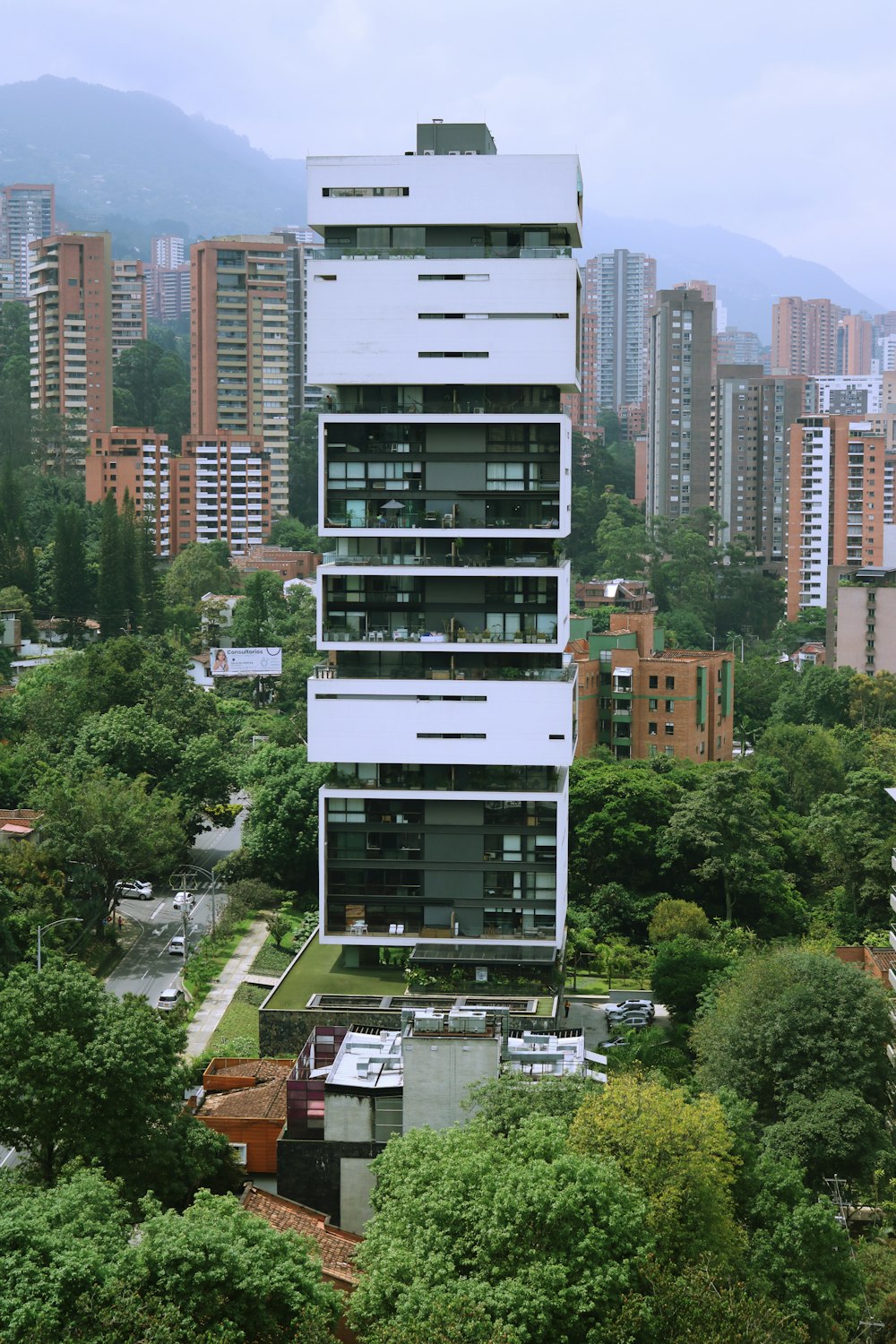 a tall white building sitting in the middle of a forest