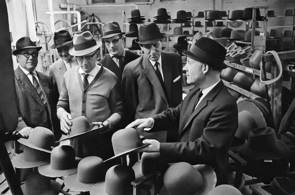 a group of men in suits and hats looking at hats