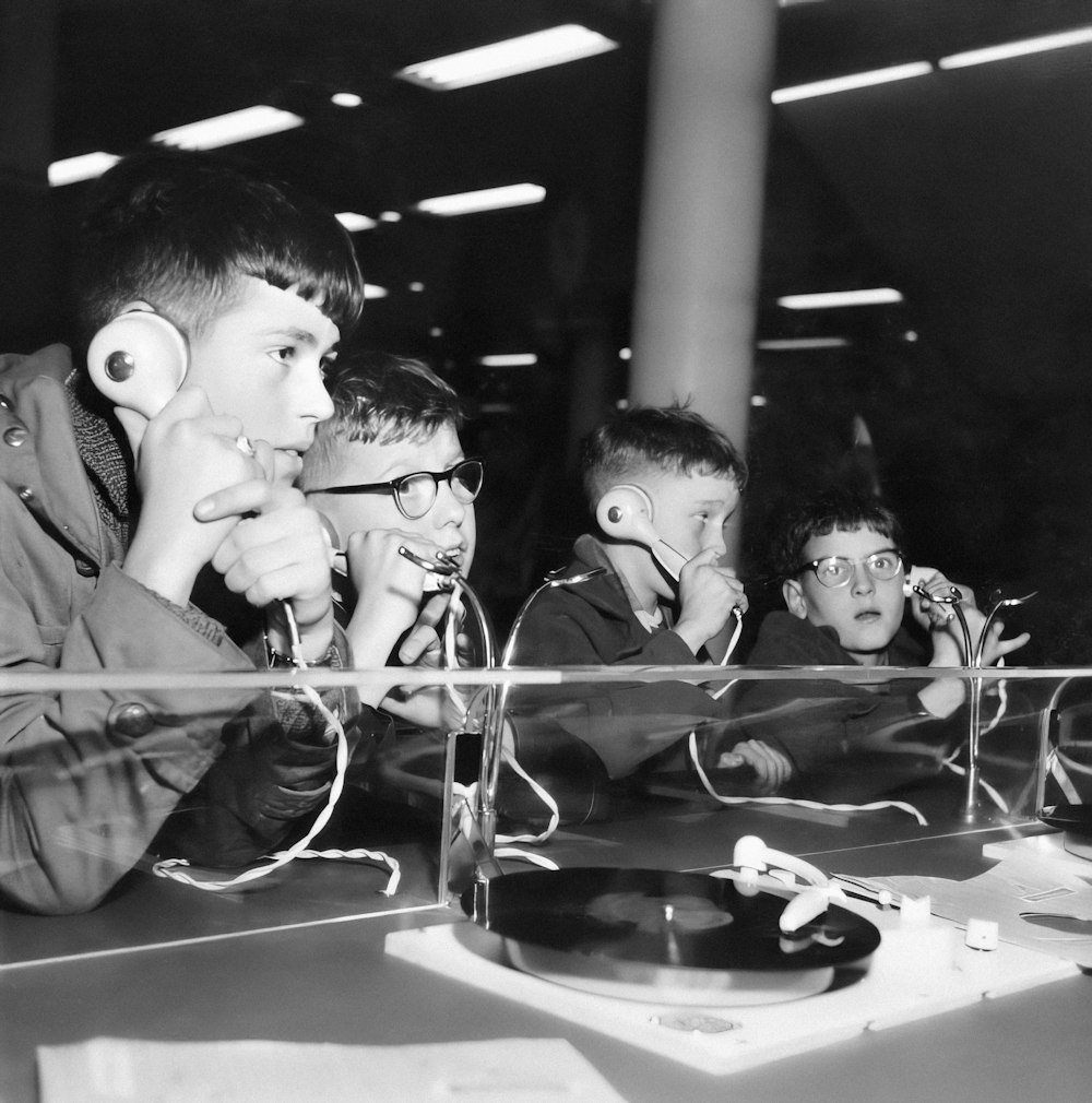 a black and white photo of a group of kids playing with headphones