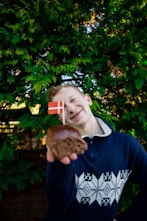 a young man holding a donut with a flag on it