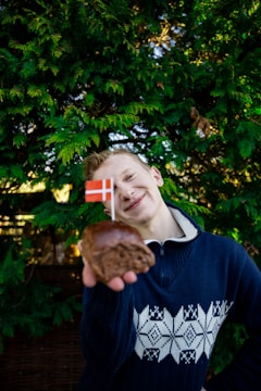 a young man holding a donut with a flag on it