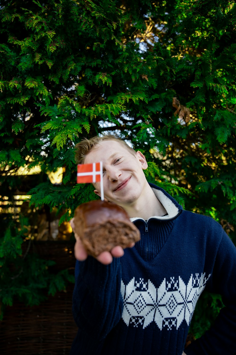 a young man holding a donut with a flag on it