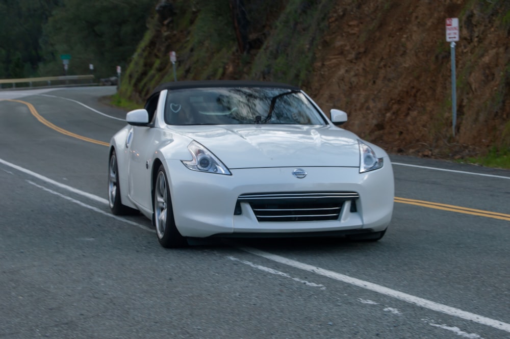 a white sports car driving down the road