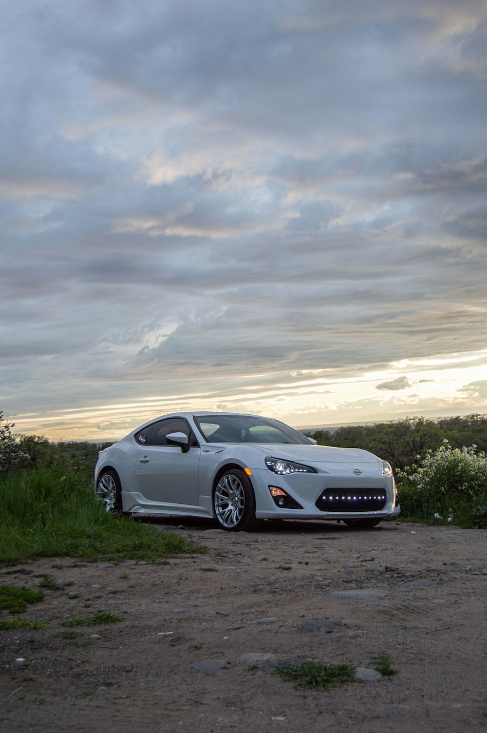 a white sports car parked on a dirt road
