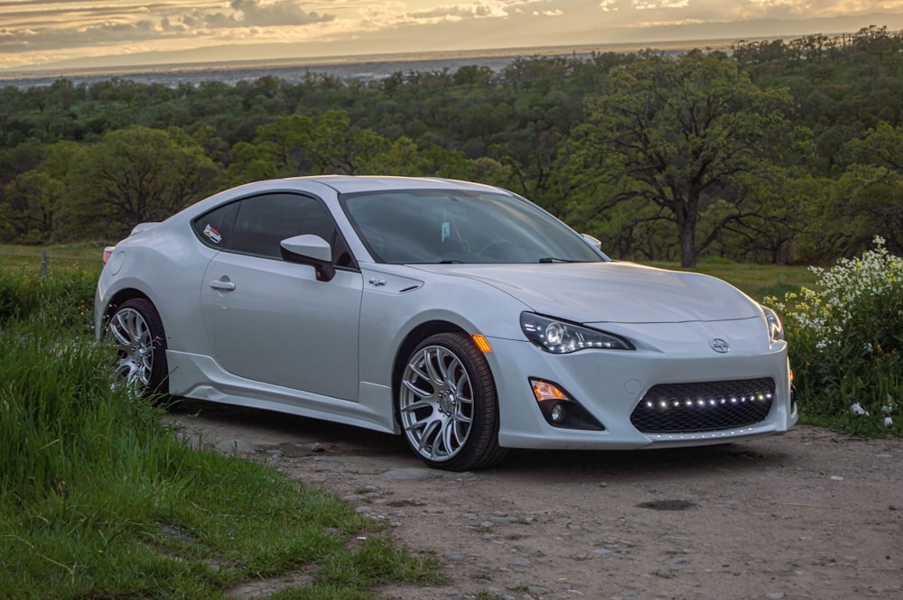 a white sports car parked on a dirt road