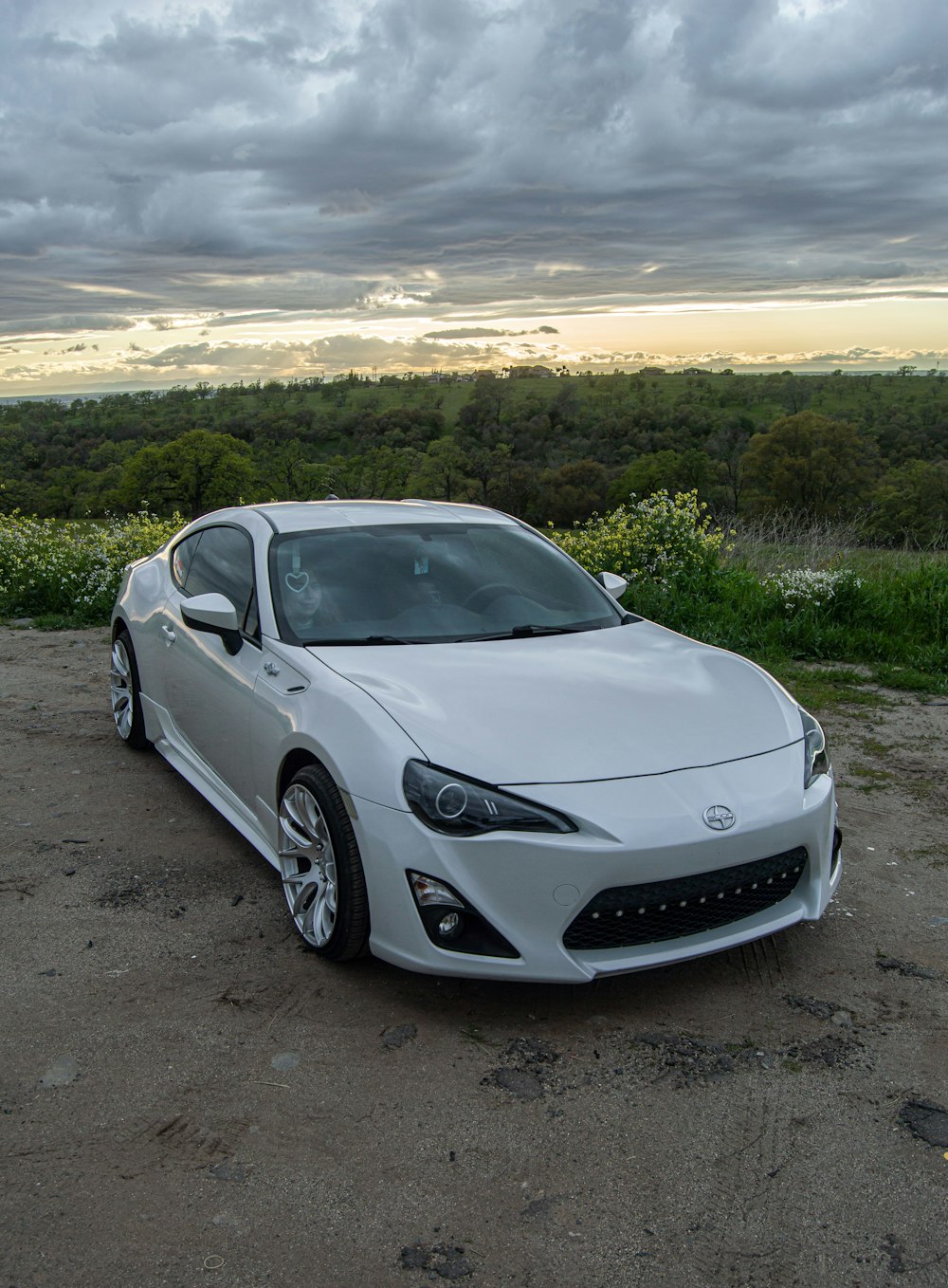 a white sports car parked on top of a dirt field