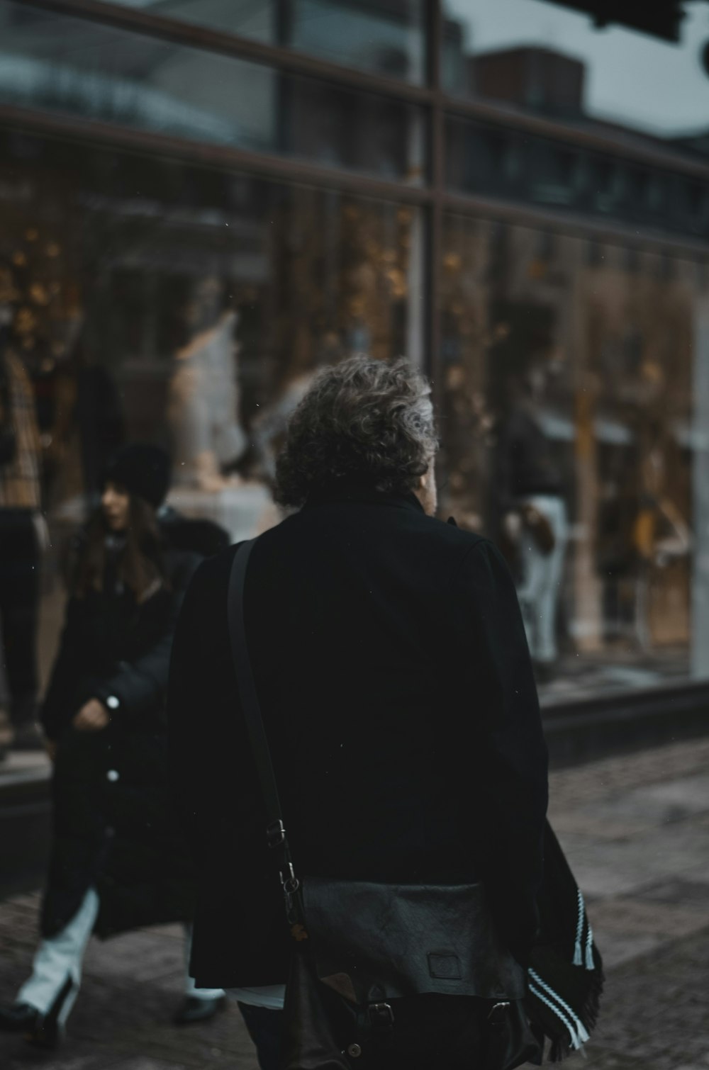 a woman walking down a street past a store front