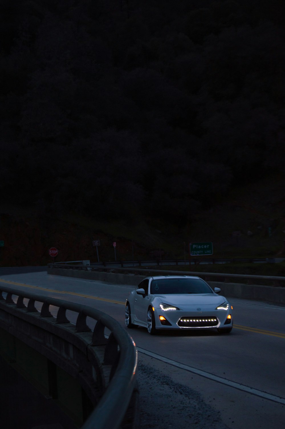 a white car driving down a highway at night