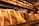 A display of elegantly packaged golden chocolate bars prominently arranged, with a shelf lined with more products in the background. The setting suggests a specialty chocolate shop or a gourmet store with a warm, inviting atmosphere.