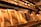 A display of elegantly packaged golden chocolate bars prominently arranged, with a shelf lined with more products in the background. The setting suggests a specialty chocolate shop or a gourmet store with a warm, inviting atmosphere.