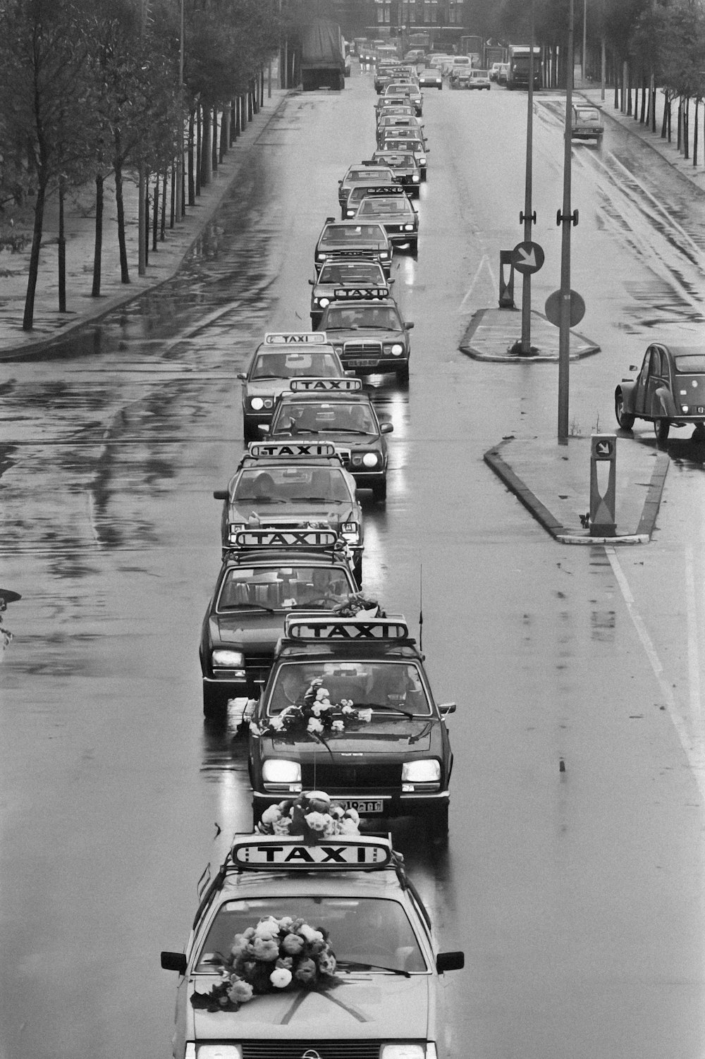 a black and white photo of a line of cars in the rain