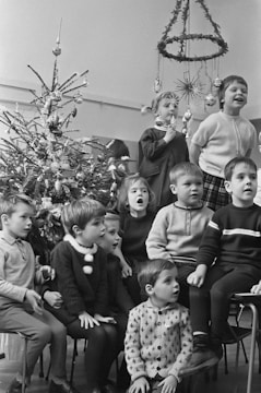 Children gathered around a storyteller sharing Christmas tales by a decorated tree.
