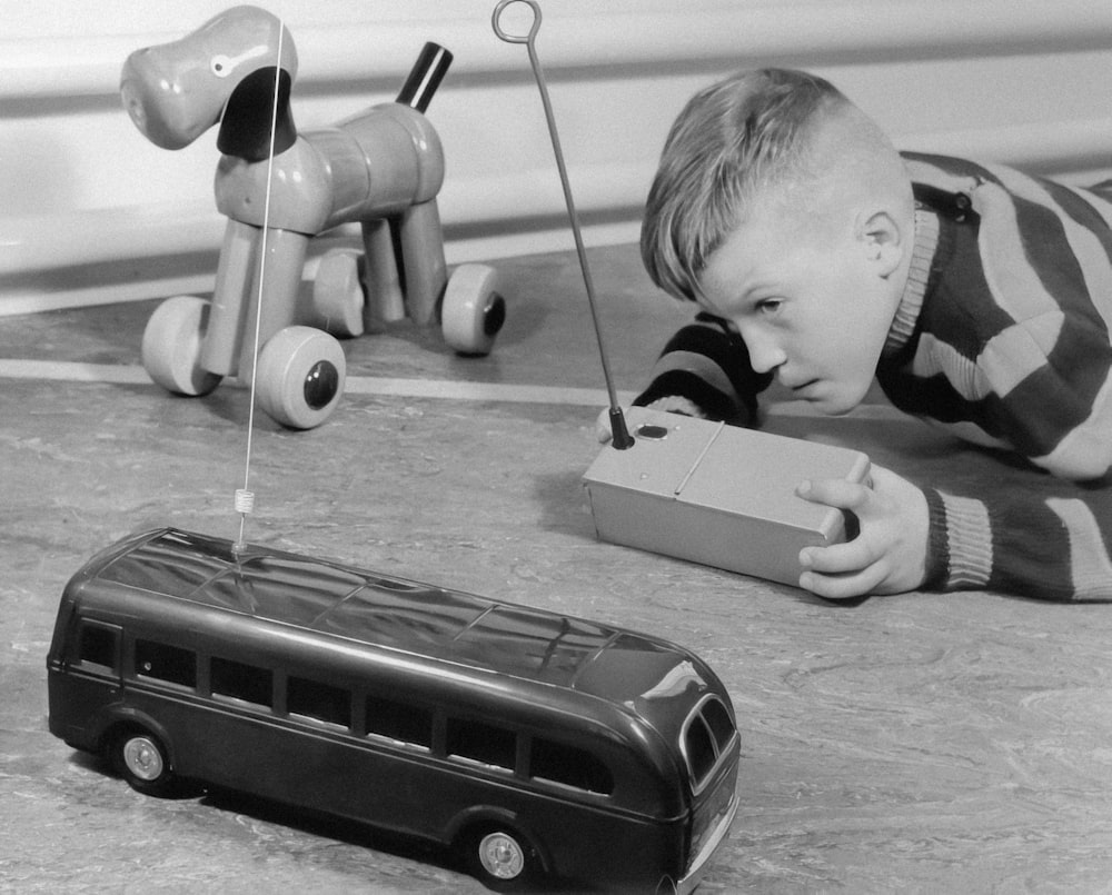 a young boy laying on the floor next to a toy bus