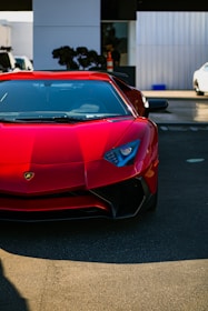 A shiny red Maruti Suzuki Swift parked on a sunny street.