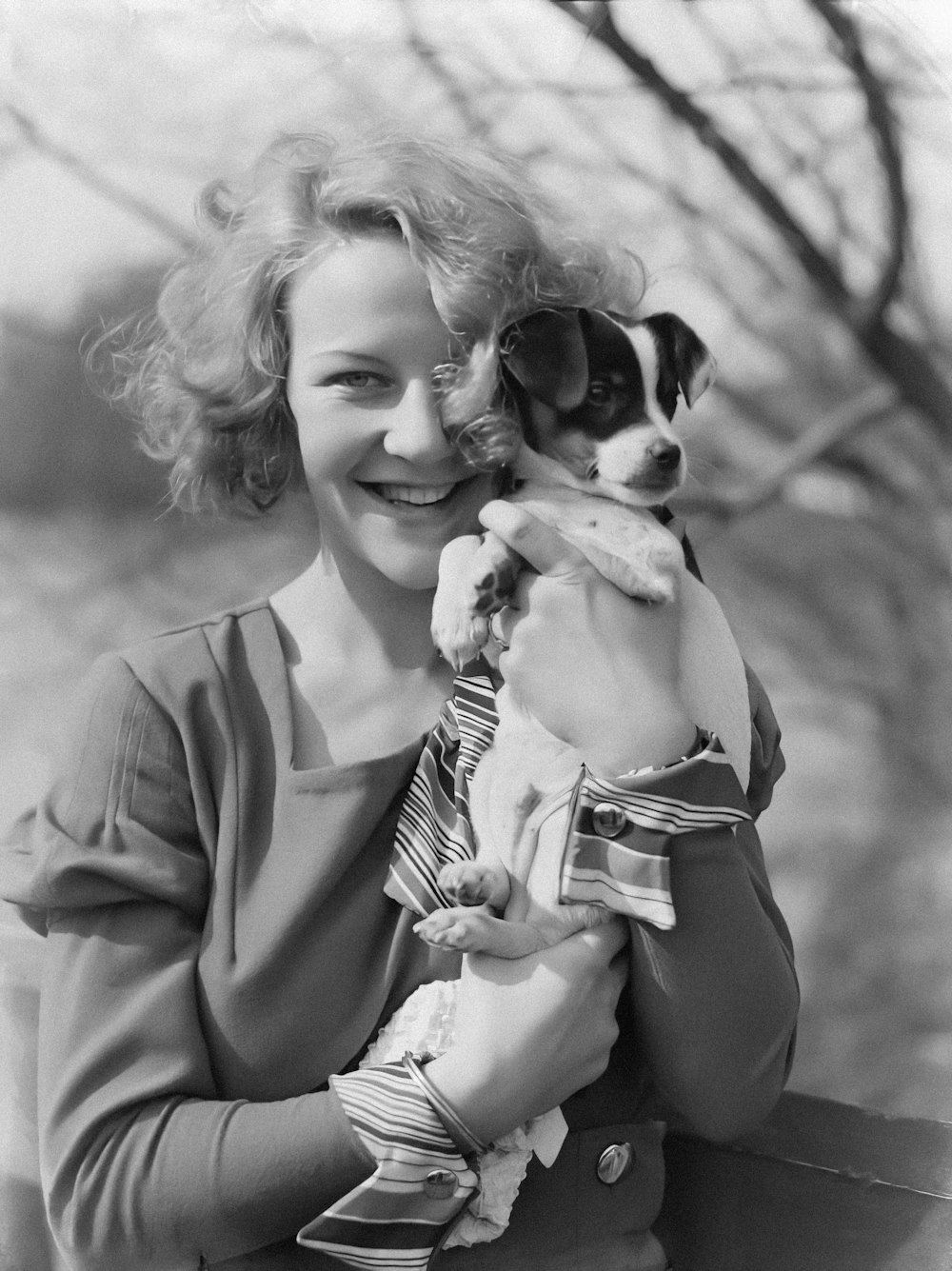 a black and white photo of a woman holding a dog