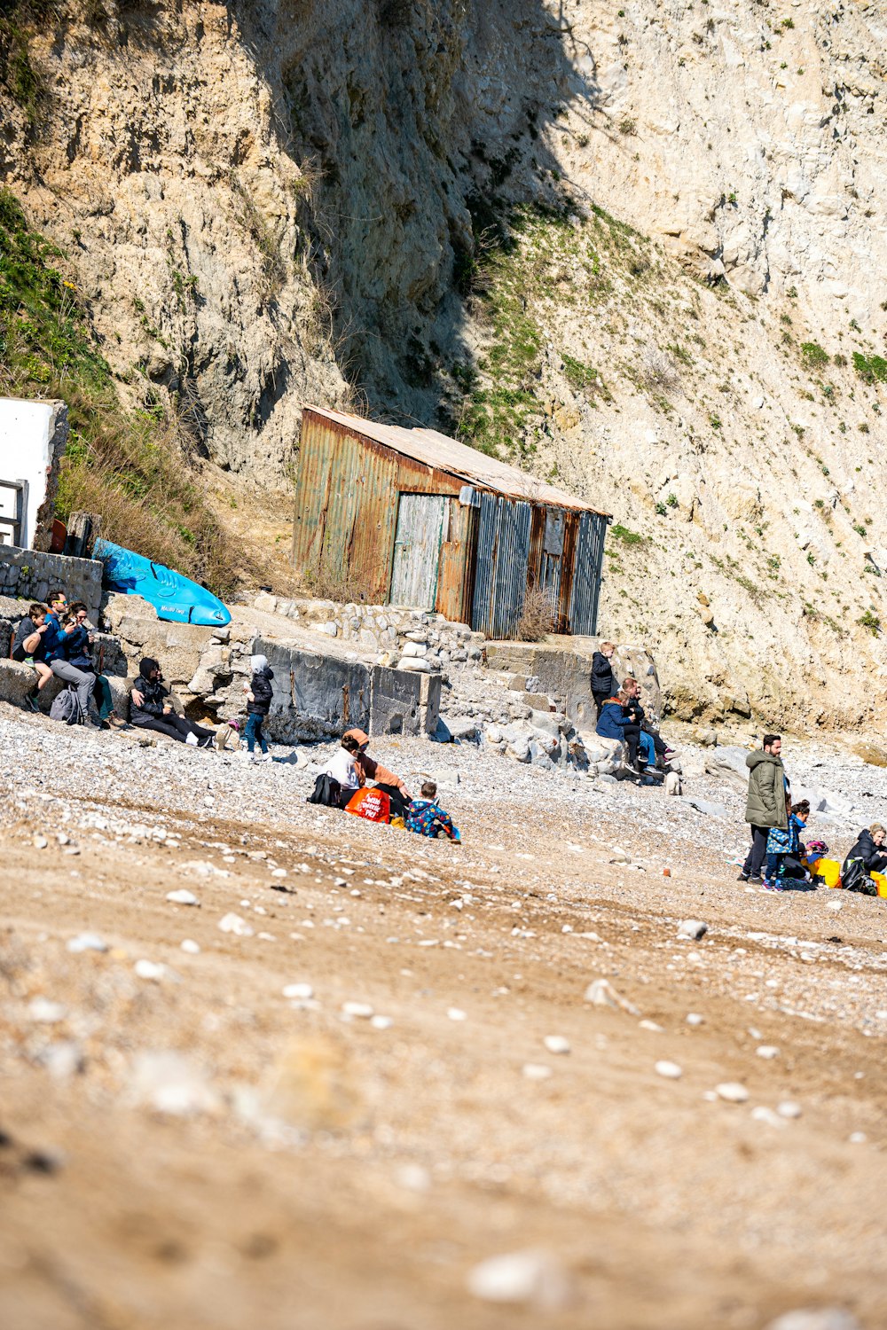 a group of people sitting on a beach next to a cliff