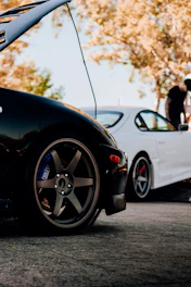 Close-up of a mechanic changing brake pads on a car wheel outdoors with sunlight filtering through trees.