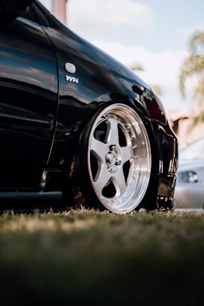 Detail of a car's polished wheel with nature softly blurred in the background.