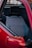 A close-up view of a car's interior, featuring a seat with a plaid fabric pattern. The seat includes a black headrest and is surrounded by a red car door.