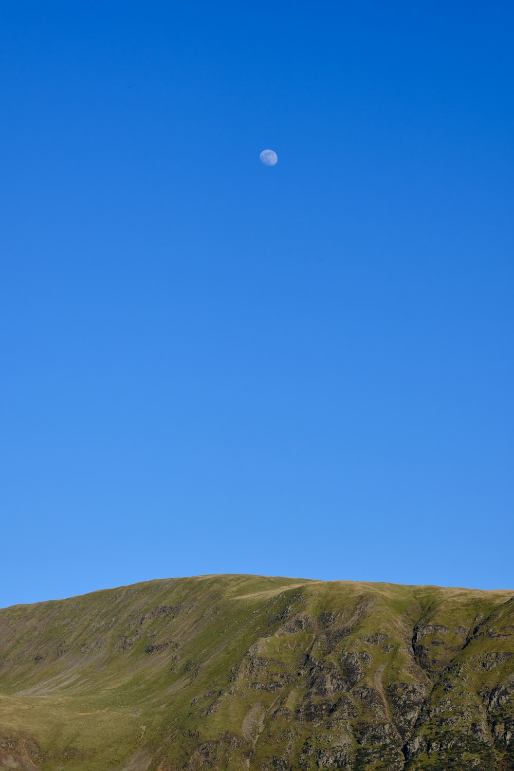 a hill with a half moon in the sky
