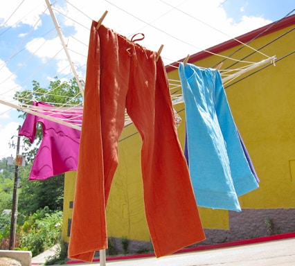 A vibrant summer scene with colorful t-shirts and hoodies hanging on a clothesline under bright sunlight.