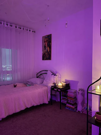 A cozy bedroom scene with sensuous lingerie laid out beside scented candles and roses.