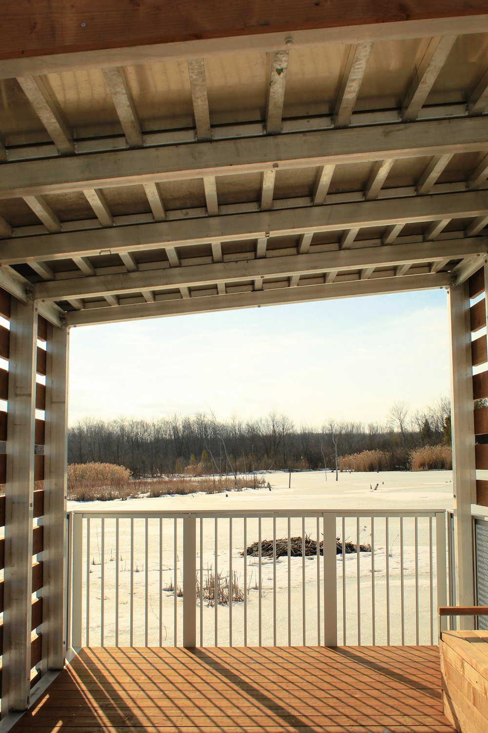 a view of a snowy field from a covered porch