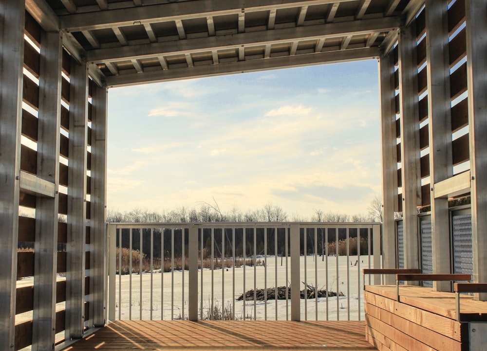 a wooden deck with a metal railing and a snow covered field