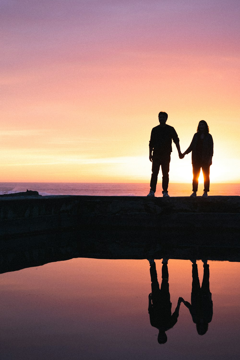 a couple holding hands while standing on a dock