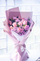 A bouquet of fresh lavender and pink roses resting on a silky lace cloth.