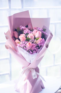 A bouquet of fresh lavender and pink roses resting on a silky lace cloth.