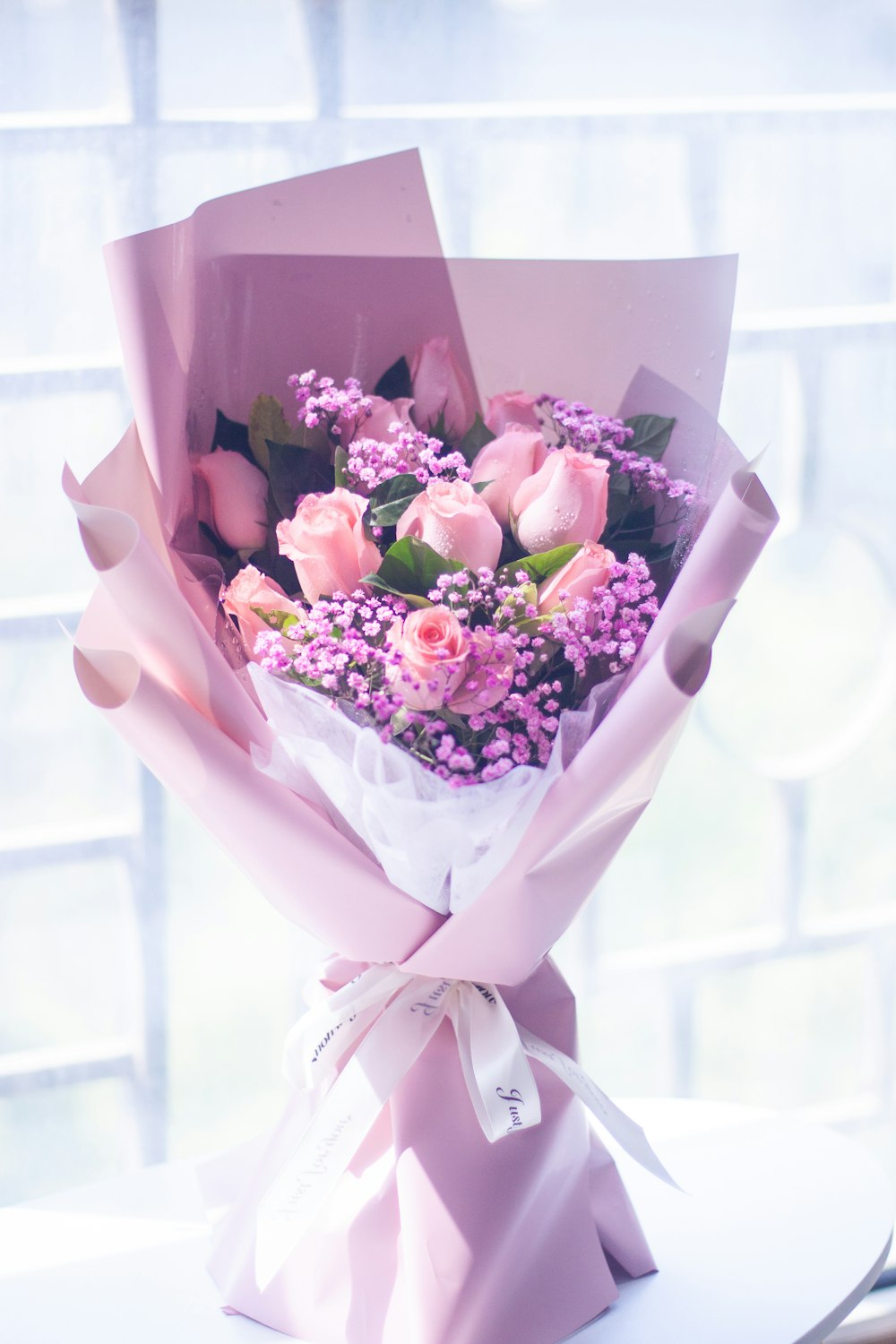 a bouquet of pink roses wrapped in pink paper