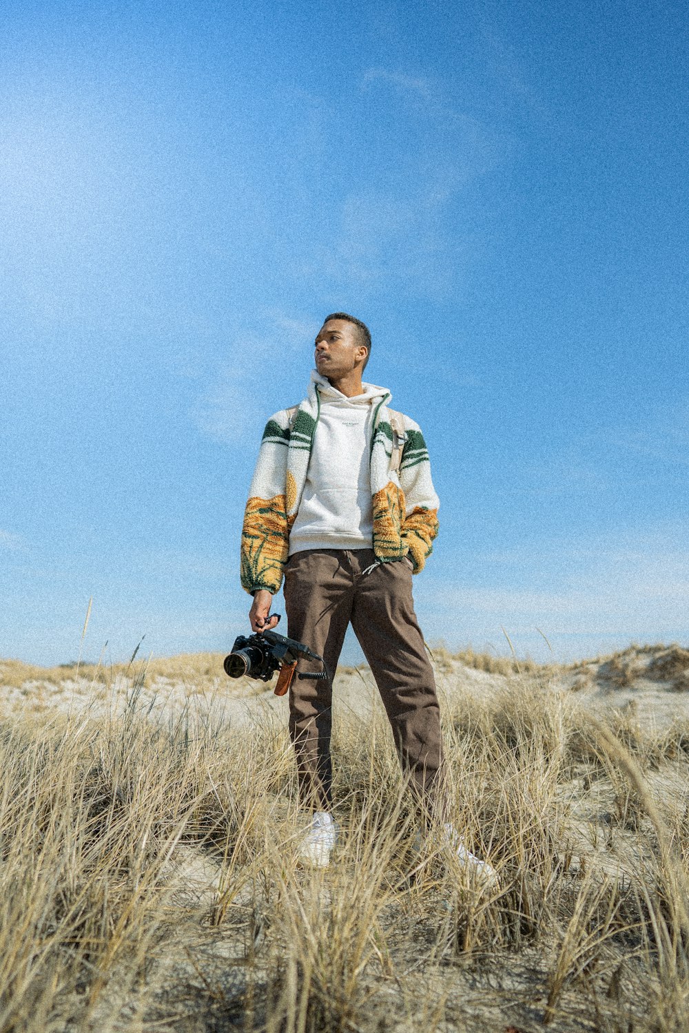 a man standing in a field holding a camera