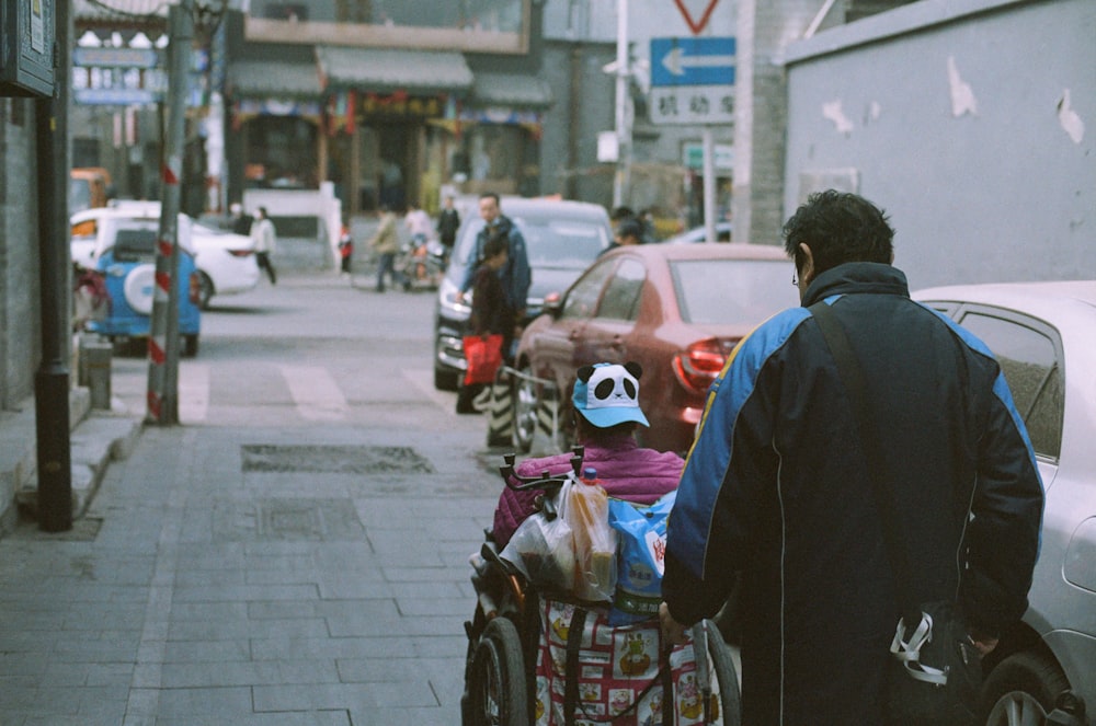 a man pushing a child in a stroller down a street