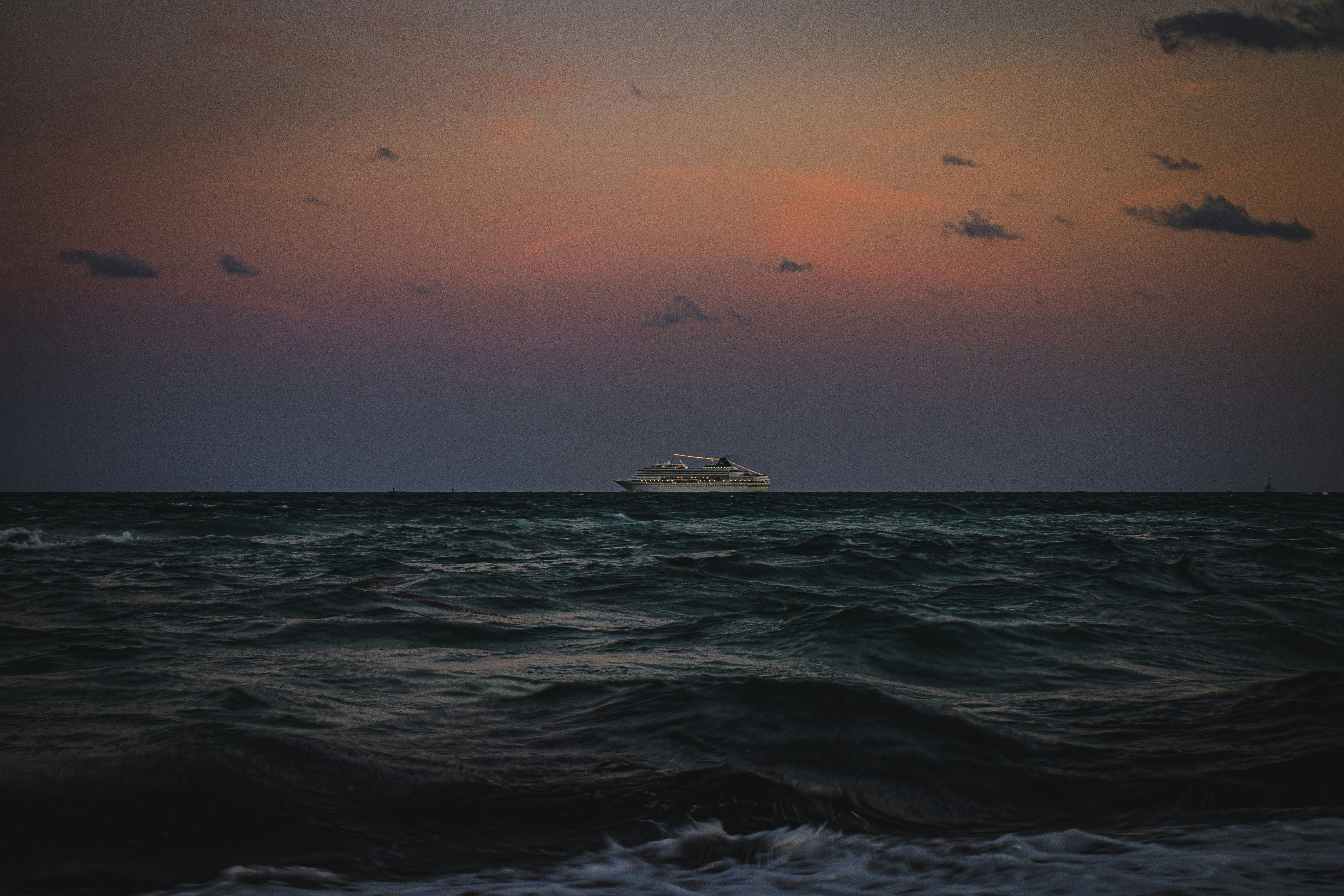Cruise ship sailing toward the horizon at sunset