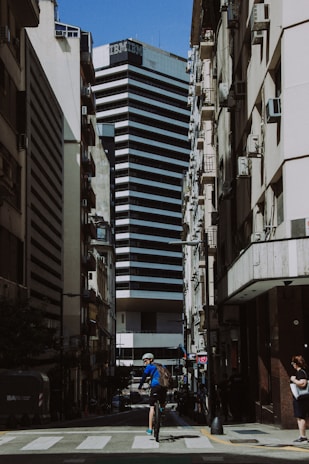 a man riding a bike down a street next to tall buildings