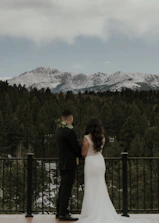 A wedding planner discussing details with a couple overlooking a scenic mountain view.