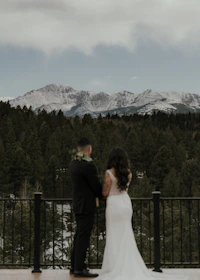 A wedding planner discussing details with a couple overlooking a scenic mountain view.