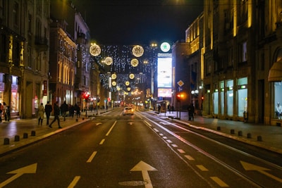 A city street illuminated by bright, welcoming lights at night.